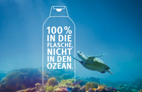 Eine Meeresschildkröte schwimmt in der Nähe eines Korallenriffs unter Wasser. Der überlagerte Text innerhalb des Umrisses einer Flasche lautet: 100 % IN DIE FLASCHE, NICHT IN DEN OZEAN. (Englisch: 100 % in die Flasche, nicht in den Ozean.) Werner & Mertz unterstützt saubere Ozeane.
