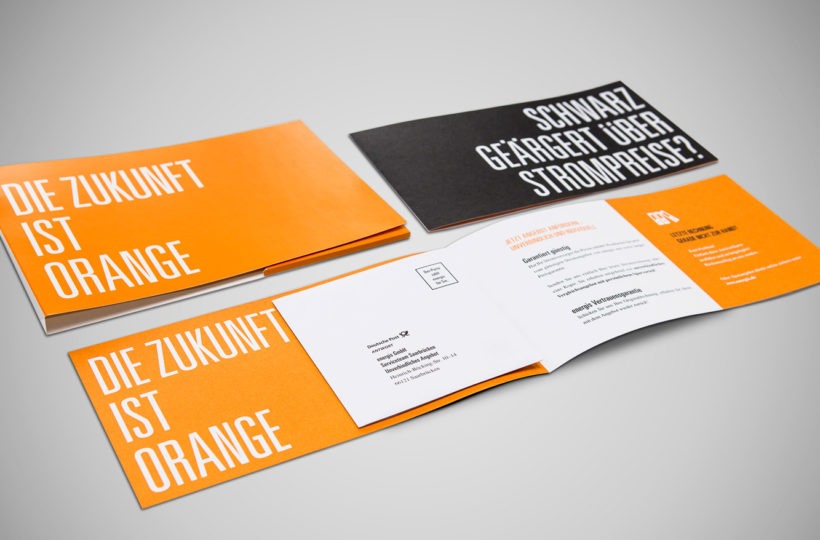 Drei Broschüren mit fettgedrucktem deutschen Text sind auf grauem Hintergrund abgebildet. Auf den orangefarbenen Umschlägen steht Die Zukunft ist Orange. Auf einem schwarzen Umschlag steht Schwarz geärgert über Strompreise? Die Innenseiten enthalten Direktmarketing- und Geschäftsinformationen.