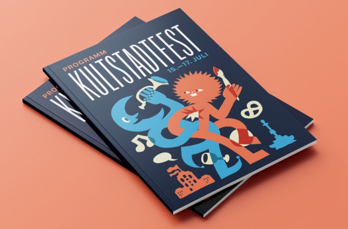 Stapel von Kultstadtfest-Programmheften mit bunten, abstrakten Illustrationen und dem fetten Text "KULTSTADTFEST 15.-17. JULI" auf dem Umschlag, vor einem pfirsichfarbenen Hintergrund.