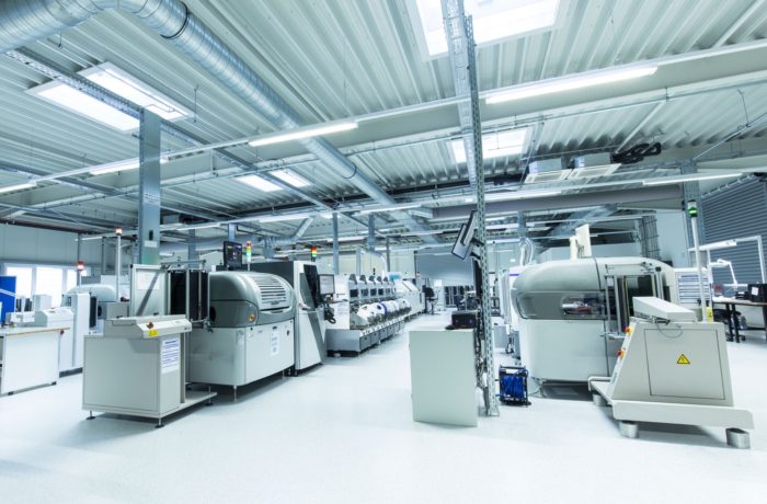 Eine geräumige, moderne Fabrikhalle mit großen Industriemaschinen, heller Deckenbeleuchtung und hellem Bodenbelag. Verschiedene automatisierte Geräte und Arbeitsstationen sind in geordneten Reihen angeordnet. Eine geräumige, moderne Fabrikhalle mit großen Industriemaschinen, heller Deckenbeleuchtung und hellem Bodenbelag. Verschiedene automatisierte Geräte und Arbeitsstationen sind in geordneten Reihen angeordnet.