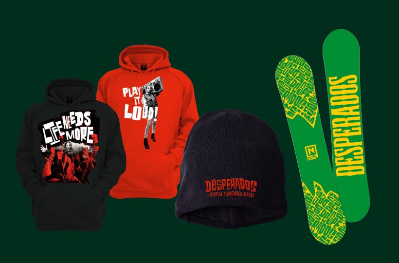 Zwei Kapuzenpullis (ein schwarzer mit der Aufschrift LIFE NEEDS MORE und ein roter mit der Aufschrift PLAY IT LOUD), eine marineblaue Mütze mit dem Schriftzug DESPERADOS und ein Paar grün-gelbe Snowboards mit dem Logo der Desperados.