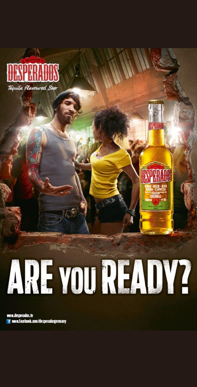 Ein Mann und eine Frau tanzen in einem lebhaften Club, umgeben von zerrissenen Wandkanten, neben einer Flasche Desperados-Bier. Unten steht in Fettschrift "ARE you READY?" und oben das Desperados-Logo.