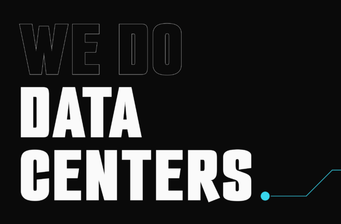 Ein modernes Rechenzentrumsgebäude mit begrünten Wänden und hohen Schornsteinen, auf dem das „Data Castle“-Logo zu sehen ist. Der Schriftzug lautet „WE DO DATA CENTERS“ und enthält das Logo der DCP Data Center Partners-Website auf schwarzem Hintergrund.