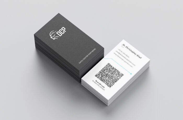 Ein Stapel Visitenkarten hebt das OCP-Logo und DATA CENTER PARTNERS hervor. Eine weiße Karte enthält die Kontaktdaten von Dr. Christopher Bisel, einen großen QR-Code, der auf die Website verweist, und unterstreicht auf einer hellgrauen Fläche die Kompetenz des Unternehmens im Bereich Rechenzentren. Ein Stapel Visitenkarten hebt das OCP-Logo und DATA CENTER PARTNERS hervor. Eine weiße Karte enthält die Kontaktdaten von Dr. Christopher Bisel, einen großen QR-Code, der auf die Website verweist, und unterstreicht auf einer hellgrauen Fläche die Kompetenz des Unternehmens im Bereich Rechenzentren.