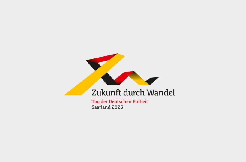 Ein abstraktes Band in den Farben der deutschen Flagge bildet eine dynamische Form über dem Text Zukunft durch Wandel. Darunter steht Tag der Deutschen Einheit, Saarland 2025 - ein ideales Motiv für Eventmarketing. Der Hintergrund ist hellgrau.