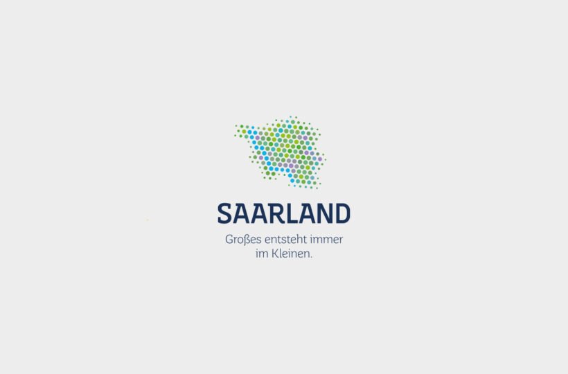 Logo mit einer Ansammlung von blauen, grünen und gelben Punkten, die die Form des Saarlandes bilden, über dem Text SAARLAND und dem deutschen Slogan Großes entsteht immer im Kleinen - moderne Logogestaltung auf hellgrauem Hintergrund.